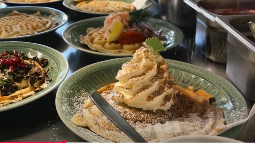 Photo credit: screenshot from a video taken in a Swedish Waffle restaurant, showing their famous waffle with rhubarb compost topped with whipped cream dusted with cinnamon suga
